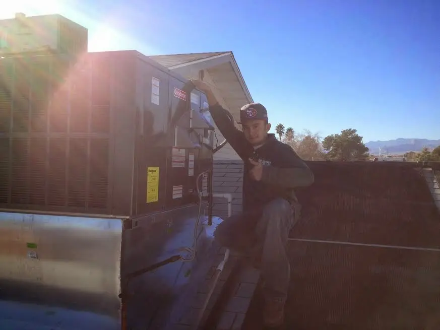 HVAC technician performing AC Tune-Up on a rooftop unit in Chowchilla
